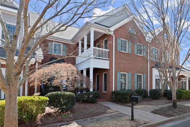 view of front of house with brick siding and a balcony