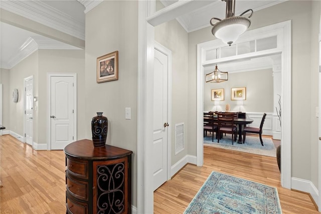 hallway with light wood-type flooring, visible vents, crown molding, and a notable chandelier