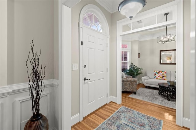 entryway featuring crown molding, a chandelier, and light wood-style floors