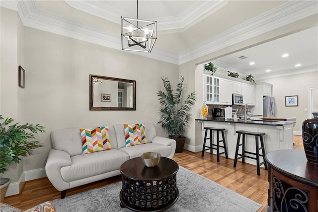 living area featuring baseboards, light wood finished floors, recessed lighting, and crown molding