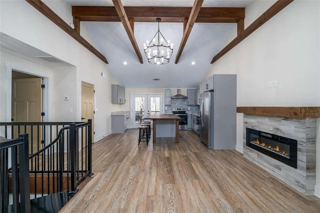 kitchen with gray cabinets, a tile fireplace, wall chimney exhaust hood, and stainless steel appliances