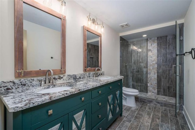 bathroom featuring vanity, toilet, and a tile shower