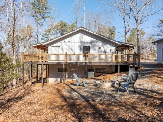 rear view of property with cooling unit, a deck, and an outdoor fire pit