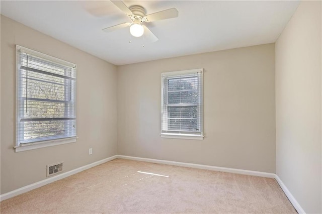 spare room featuring light carpet, plenty of natural light, visible vents, and baseboards