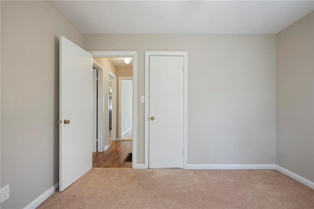 unfurnished bedroom with light carpet and baseboards