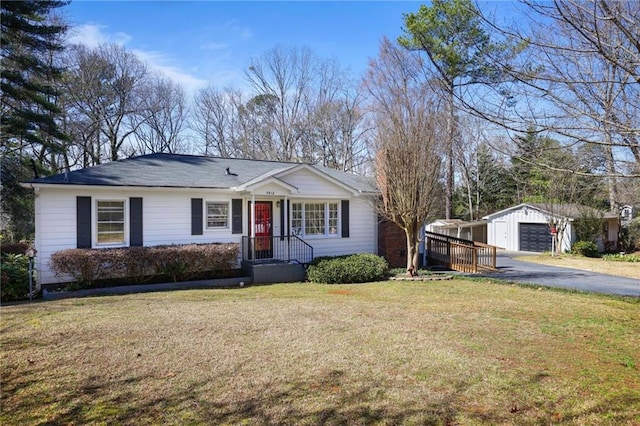 single story home with driveway, a garage, a front lawn, and an outbuilding