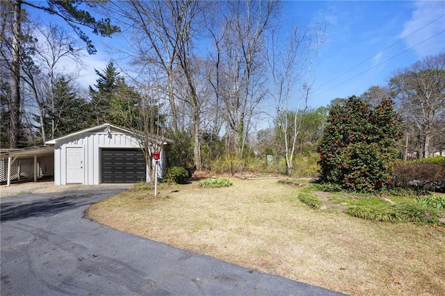 view of yard featuring a garage, a carport, aphalt driveway, and an outdoor structure