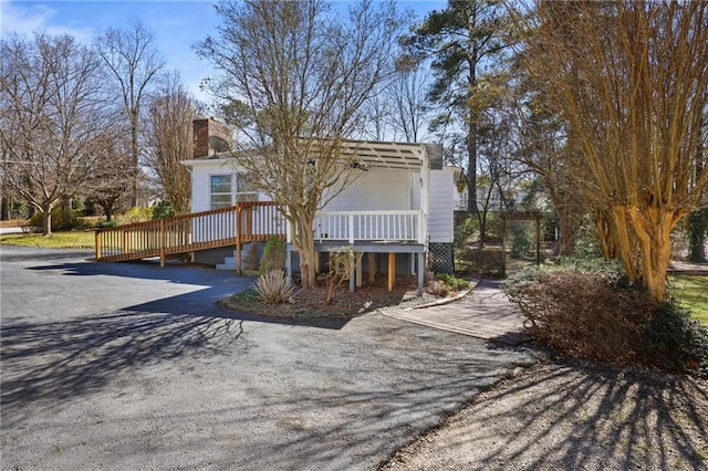 view of front of home with a deck, aphalt driveway, and a chimney