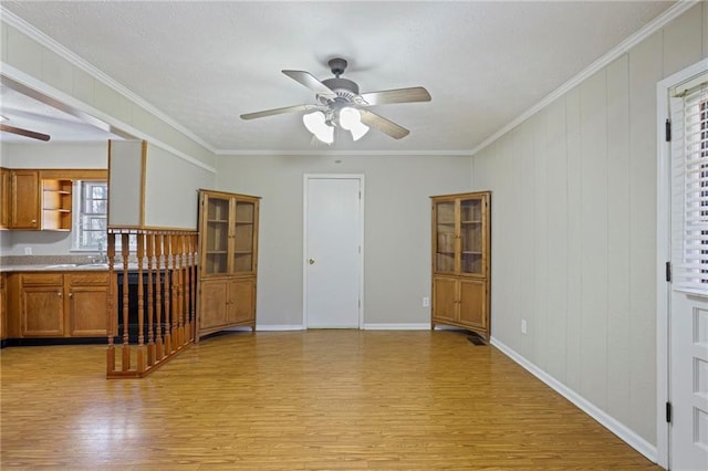 living room with crown molding, baseboards, ceiling fan, and light wood finished floors