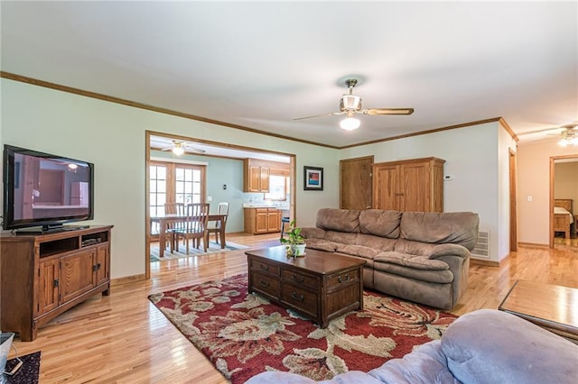 living room with light wood-type flooring, visible vents, ornamental molding, and baseboards