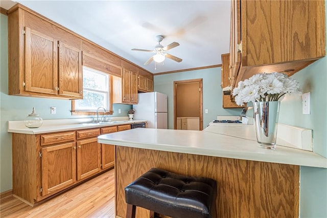 kitchen featuring white appliances, ceiling fan, a peninsula, light countertops, and light wood-style floors