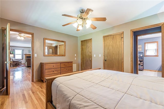 bedroom with visible vents, baseboards, a ceiling fan, light wood-style flooring, and multiple closets