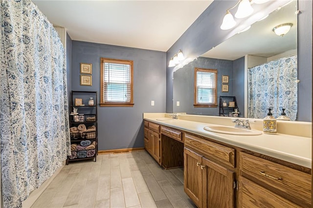 full bath with plenty of natural light, a sink, and baseboards