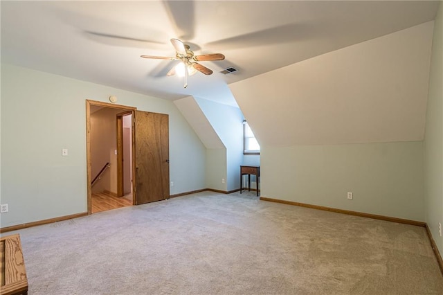 additional living space with visible vents, vaulted ceiling, light carpet, and baseboards