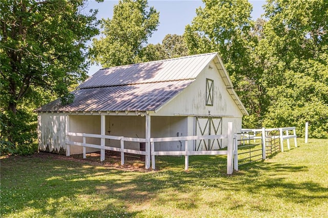 view of barn featuring fence and a lawn