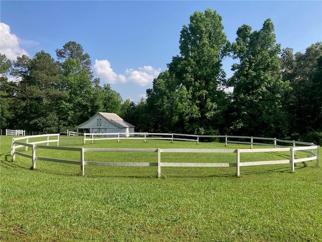 view of yard featuring fence, an outdoor structure, and a rural view