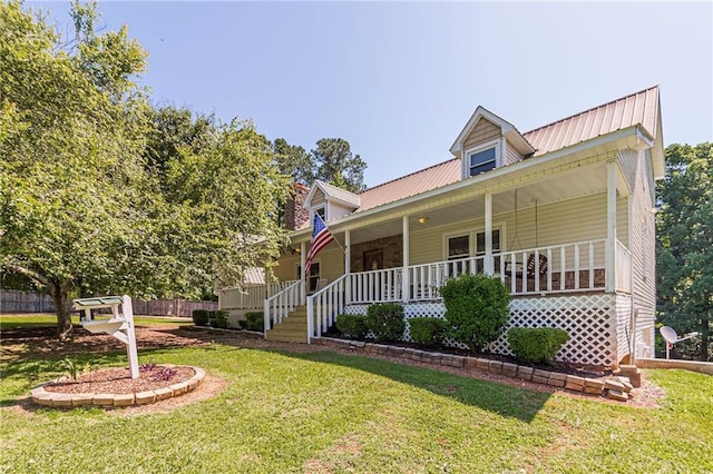 view of front of home featuring covered porch, metal roof, a front lawn, and fence