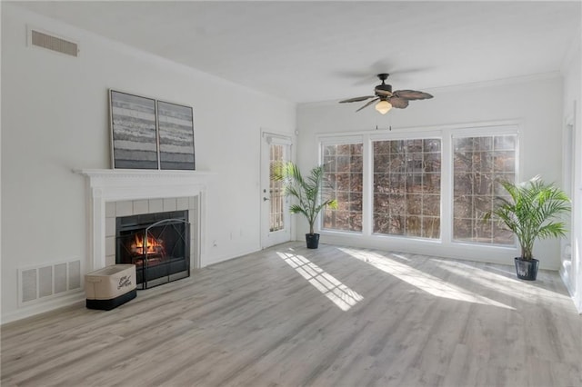 unfurnished living room with crown molding, ceiling fan, a fireplace, and light hardwood / wood-style flooring