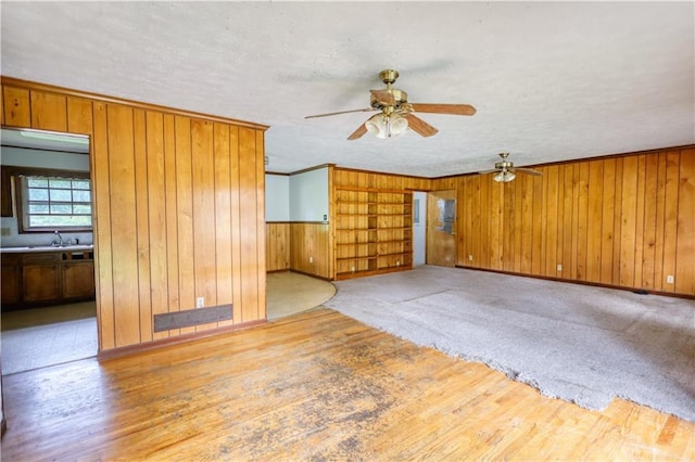 1342 Peggy Ln NW, Conyers, GA 30012 - unfurnished living room with a ceiling fan, wooden walls, wood finished floors, and a textured ceiling