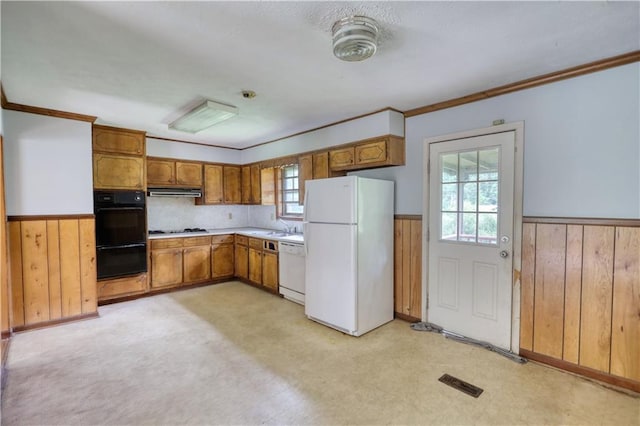 1342 Peggy Ln NW, Conyers, GA 30012 - kitchen featuring white appliances, wainscoting, wood walls, brown cabinetry, and crown molding