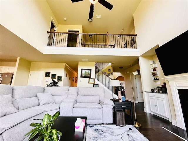 2579 Wimberley Pine Ct, Dacula, GA 30019 - living area featuring a high ceiling, stairway, a ceiling fan, dark wood finished floors, and arched walkways