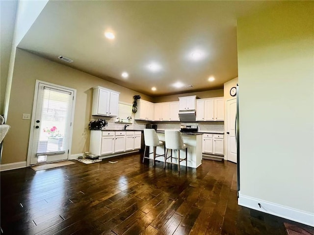 2579 Wimberley Pine Ct, Dacula, GA 30019 - kitchen featuring white cabinets, backsplash, a kitchen bar, dark wood finished floors, and recessed lighting