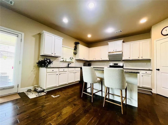 2579 Wimberley Pine Ct, Dacula, GA 30019 - kitchen with white cabinetry, a kitchen bar, dark wood-style flooring, tasteful backsplash, and recessed lighting