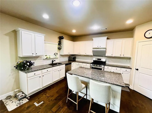 2579 Wimberley Pine Ct, Dacula, GA 30019 - kitchen featuring appliances with stainless steel finishes, a sink, white cabinetry, a kitchen bar, and backsplash