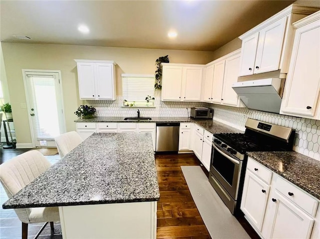 2579 Wimberley Pine Ct, Dacula, GA 30019 - kitchen with stainless steel appliances, a sink, under cabinet range hood, white cabinets, and dark wood finished floors