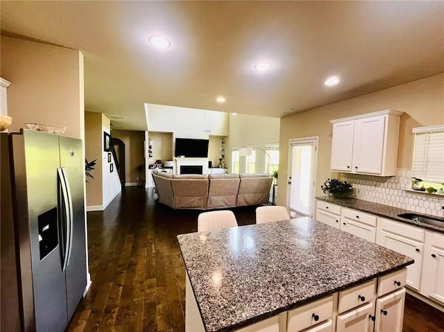 2579 Wimberley Pine Ct, Dacula, GA 30019 - kitchen with stainless steel fridge with ice dispenser, dark wood finished floors, white cabinets, decorative backsplash, and a fireplace