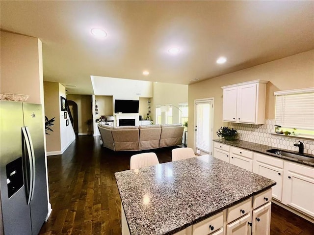2579 Wimberley Pine Ct, Dacula, GA 30019 - kitchen featuring stainless steel refrigerator with ice dispenser, a sink, dark wood finished floors, dark stone counters, and a fireplace