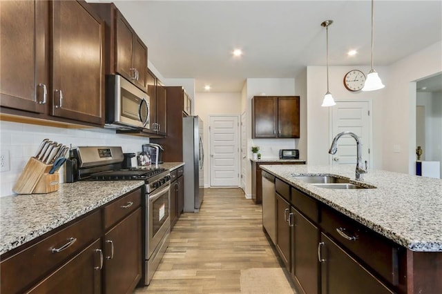115 Copeland Bnd, Jasper, GA 30143 - kitchen featuring stainless steel appliances, a sink, light wood-style flooring, decorative backsplash, and light stone countertops