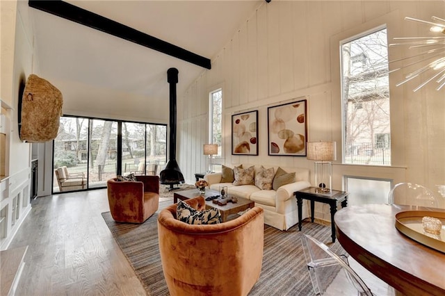 living room with beamed ceiling, wood-type flooring, a wood stove, and high vaulted ceiling