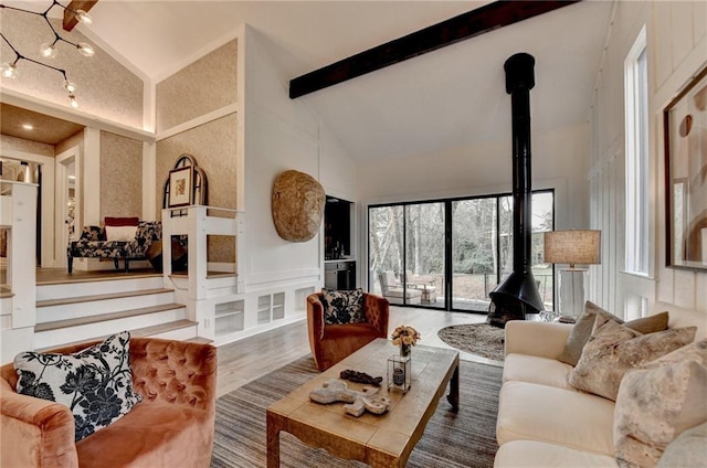 living room with beamed ceiling, a wood stove, hardwood / wood-style floors, and high vaulted ceiling