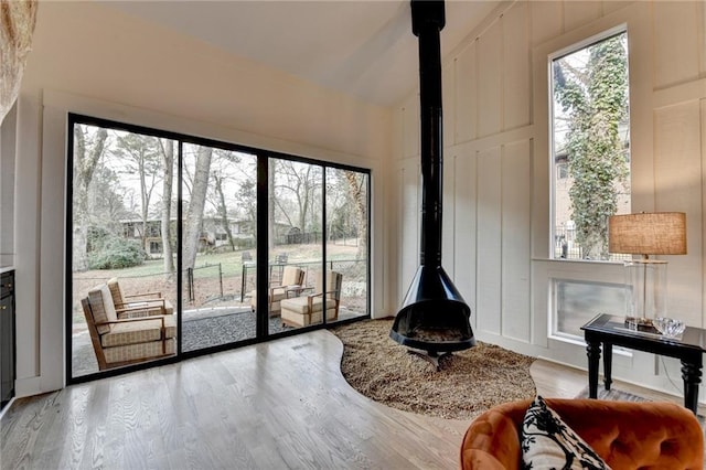 doorway to outside with lofted ceiling, a wood stove, and light hardwood / wood-style floors