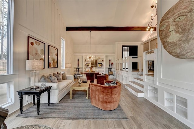 living room with beamed ceiling, a healthy amount of sunlight, hardwood / wood-style floors, and built in shelves