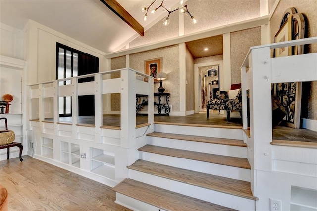 stairway with lofted ceiling, hardwood / wood-style floors, and a chandelier