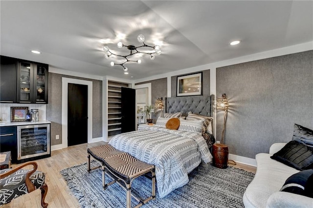 bedroom featuring two closets, light wood-type flooring, beverage cooler, and indoor bar