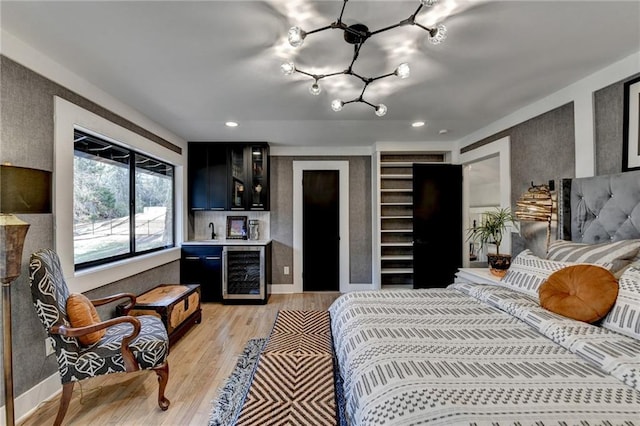 bedroom with wine cooler, indoor wet bar, and light hardwood / wood-style flooring