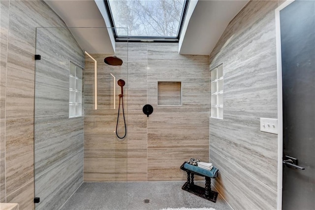 bathroom featuring a tile shower and a skylight