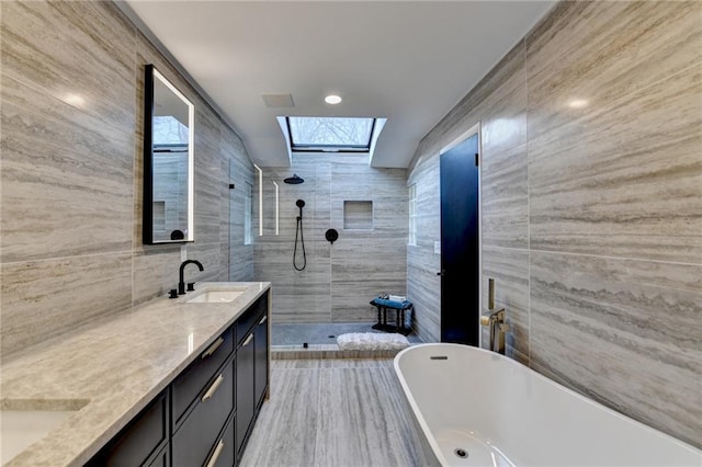 bathroom featuring vanity, shower with separate bathtub, a skylight, and tile walls