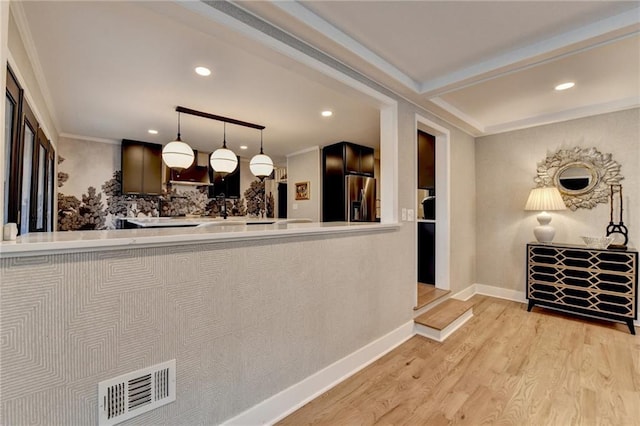 interior space with light wood-type flooring, hanging light fixtures, stainless steel fridge with ice dispenser, crown molding, and beam ceiling