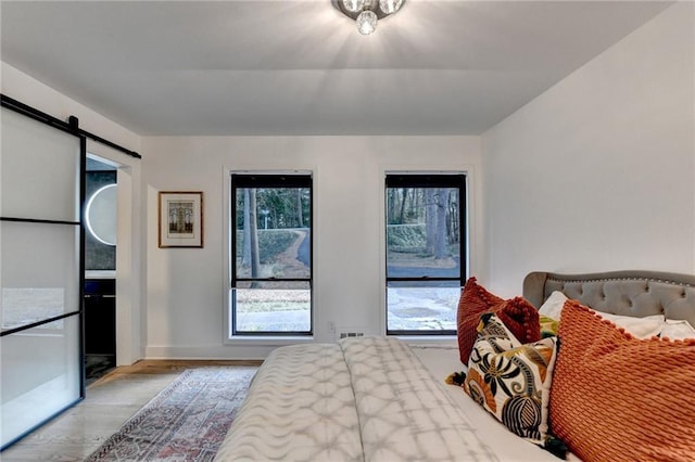 bedroom featuring a barn door and light hardwood / wood-style floors