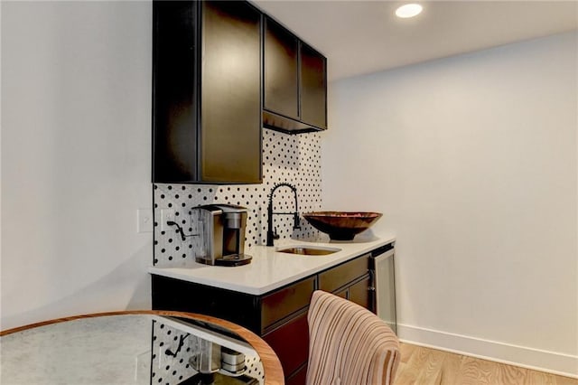 kitchen with dark brown cabinets, sink, and light hardwood / wood-style flooring