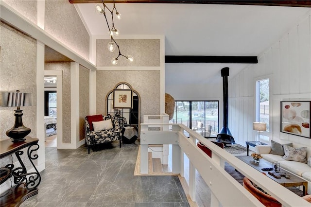 living room featuring beamed ceiling, a wood stove, and high vaulted ceiling