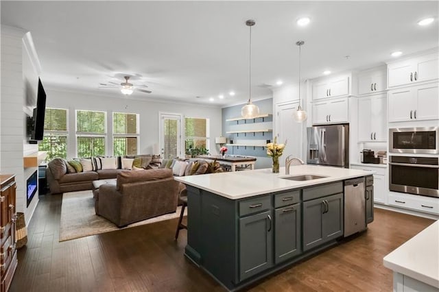 kitchen with a kitchen island with sink, hanging light fixtures, ceiling fan, appliances with stainless steel finishes, and white cabinetry