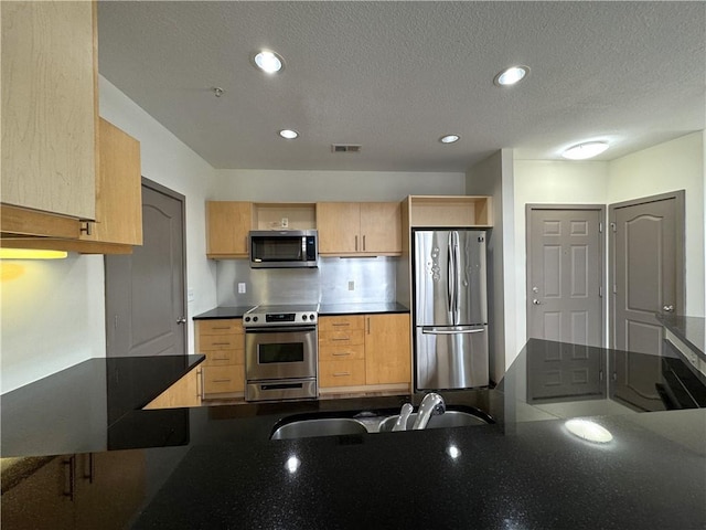 kitchen featuring stainless steel appliances, light brown cabinets, a sink, dark countertops, and recessed lighting
