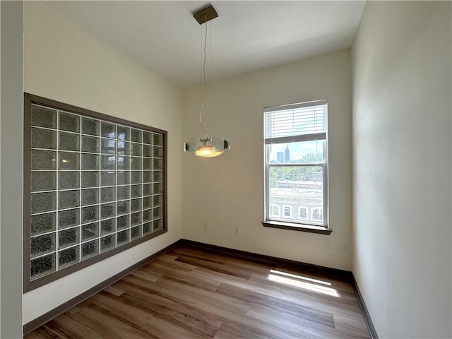 unfurnished dining area with wood finished floors and baseboards