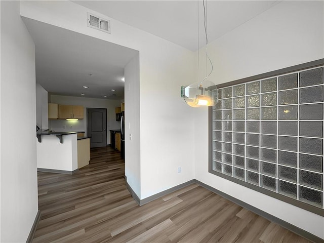 unfurnished dining area featuring dark wood-style floors and baseboards
