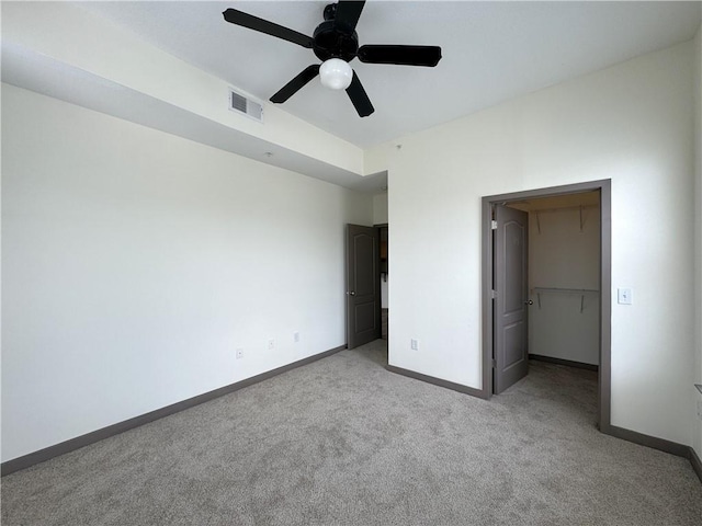 unfurnished bedroom with carpet floors, baseboards, a ceiling fan, and a spacious closet